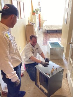 Apprentice learning hands on from an HVAC Tech on the job site