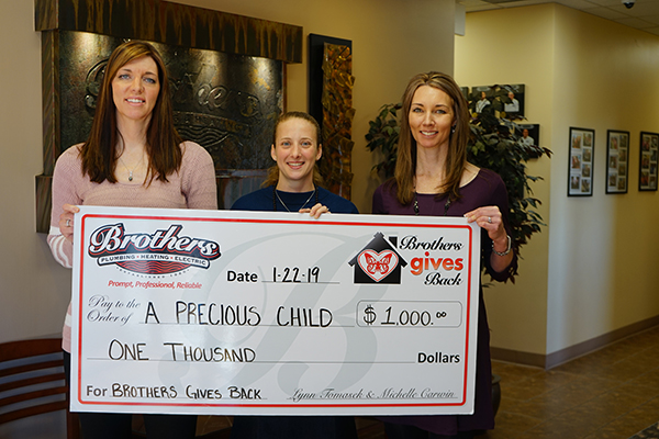 Brothers Plumbing owners hand giant check to A Precious Child campaign during January gives back